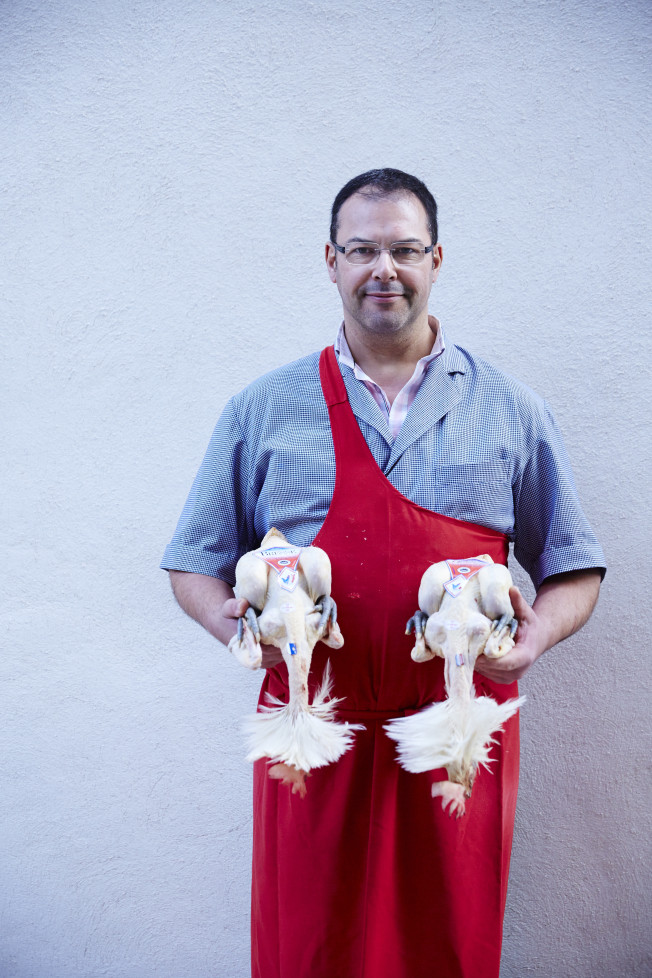 Local butcher Monsieur Vossot holds two fresh Bresse chickens, a local specialty. 